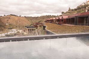 A modern building with a unique roof design, a pool area, and a hilly landscape in the background. - Longroiva Hotel Rural (Meda)
