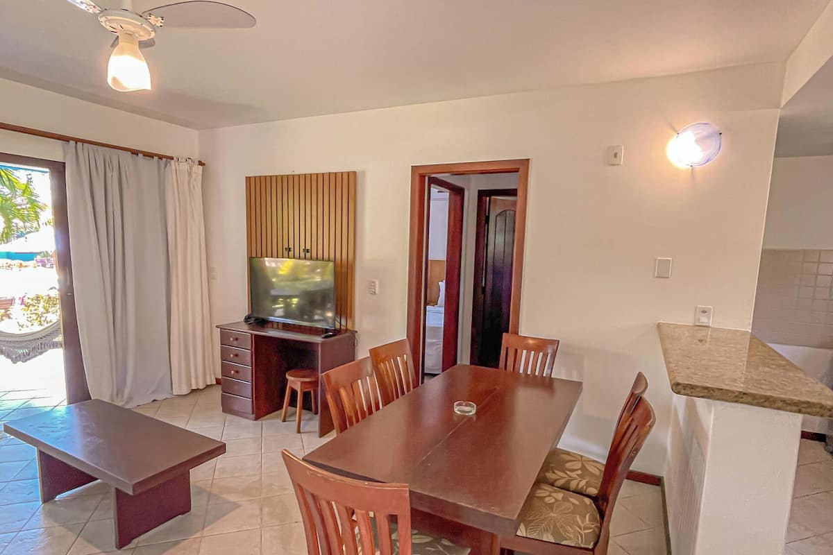 A dining area with a wooden table and chairs, a television, and a ceiling fan.
