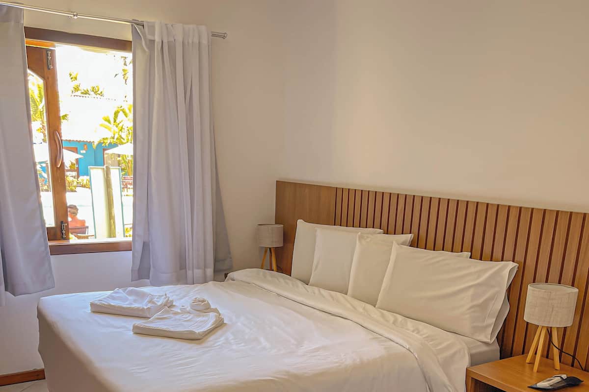 A hotel room with a large bed, a wooden headboard, and a bedside table with a lamp.