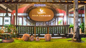 A Mar Paraiso sign with a circular design and a logo, surrounded by a wooden fence and potted plants. - Mar Paraíso Hotel (Porto Seguro)
