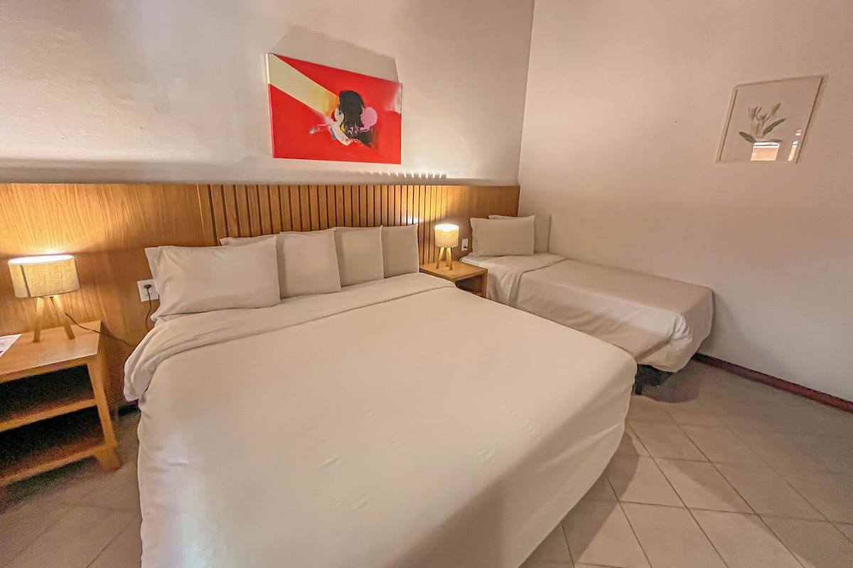 A hotel room with a large bed, two bedside tables, and a wall-mounted artwork.