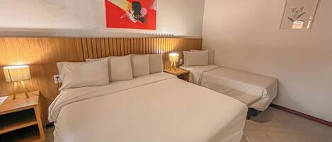 A hotel room with a large bed, two bedside tables, and a wall-mounted artwork.