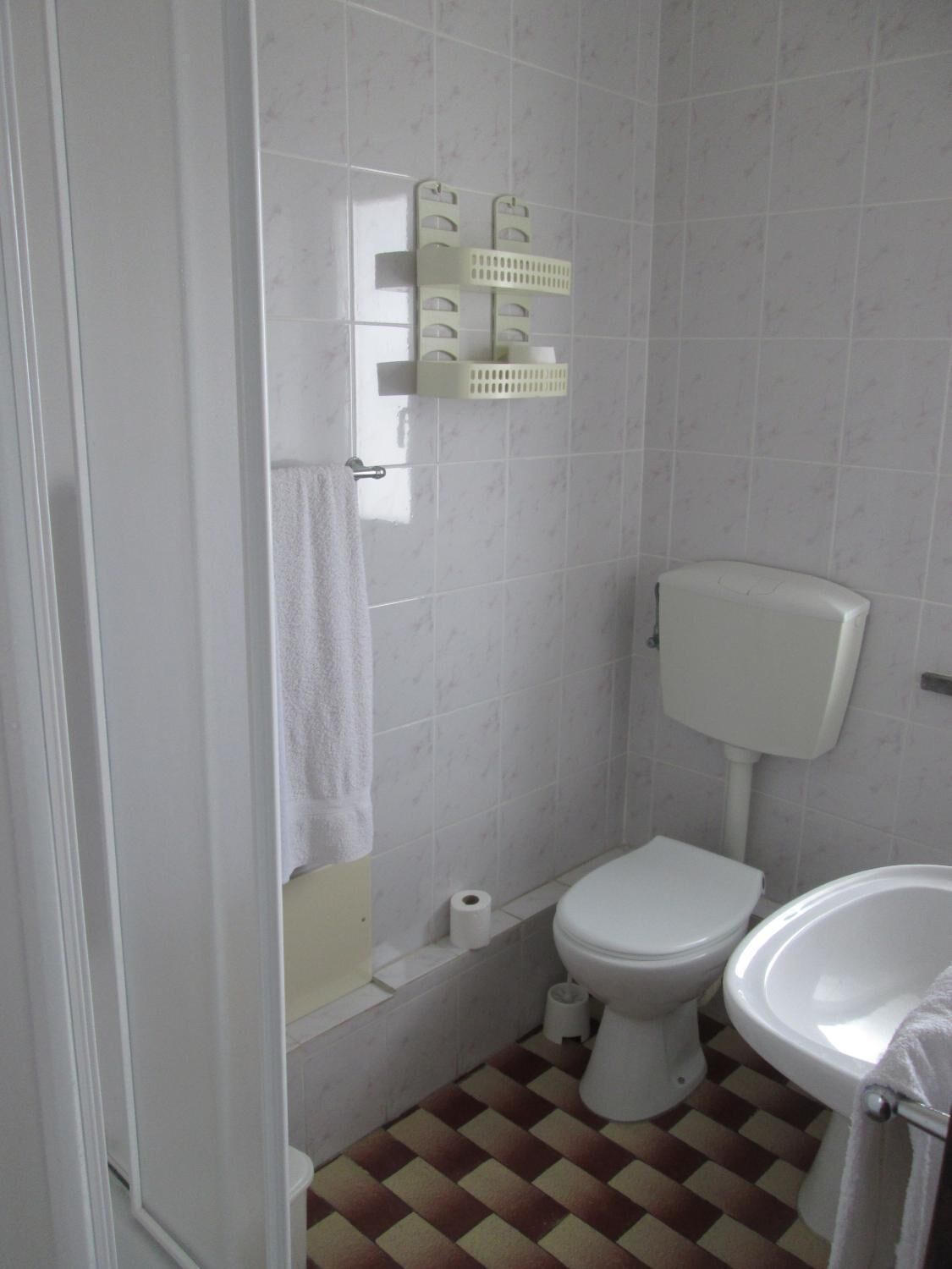A small, clean bathroom with a toilet, sink, and a towel rack.