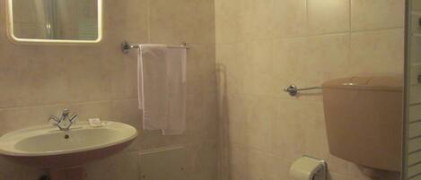 A bathroom with a sink, bidet, toilet, and a mirror with lights.