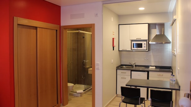 A compact kitchen with a microwave, sink, and stainless steel range hood. There is a small dining table with two chairs. - Alojamento Baleal à Vista (Peniche)