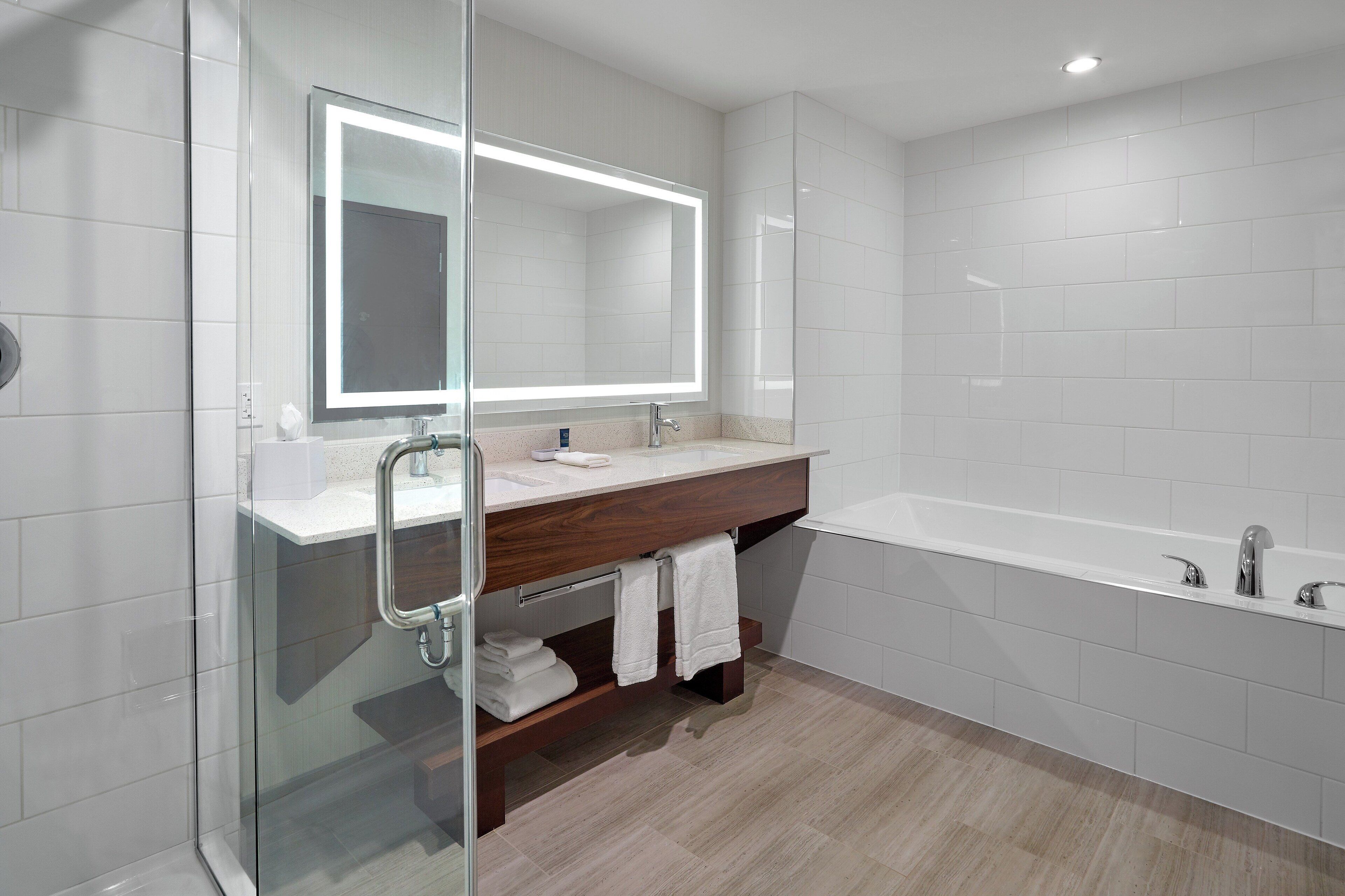 A modern bathroom with a glass shower enclosure, a vanity with a mirror, and a standalone bathtub.