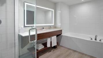 A modern bathroom with a glass shower enclosure, a vanity with a mirror, and a standalone bathtub.