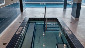An indoor swimming pool with clear lane markings, a diving board, and a view of the outdoors through large windows. - Four Points By Sheraton Sherwood Park (Sherwood Park)