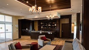 A hotel lobby with a reception desk, seating area with sofas and chairs, a patterned rug, and a chandelier. - Four Points By Sheraton Sherwood Park (Sherwood Park)