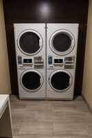 A set of four stacked front-loading washing machines in a laundry room.