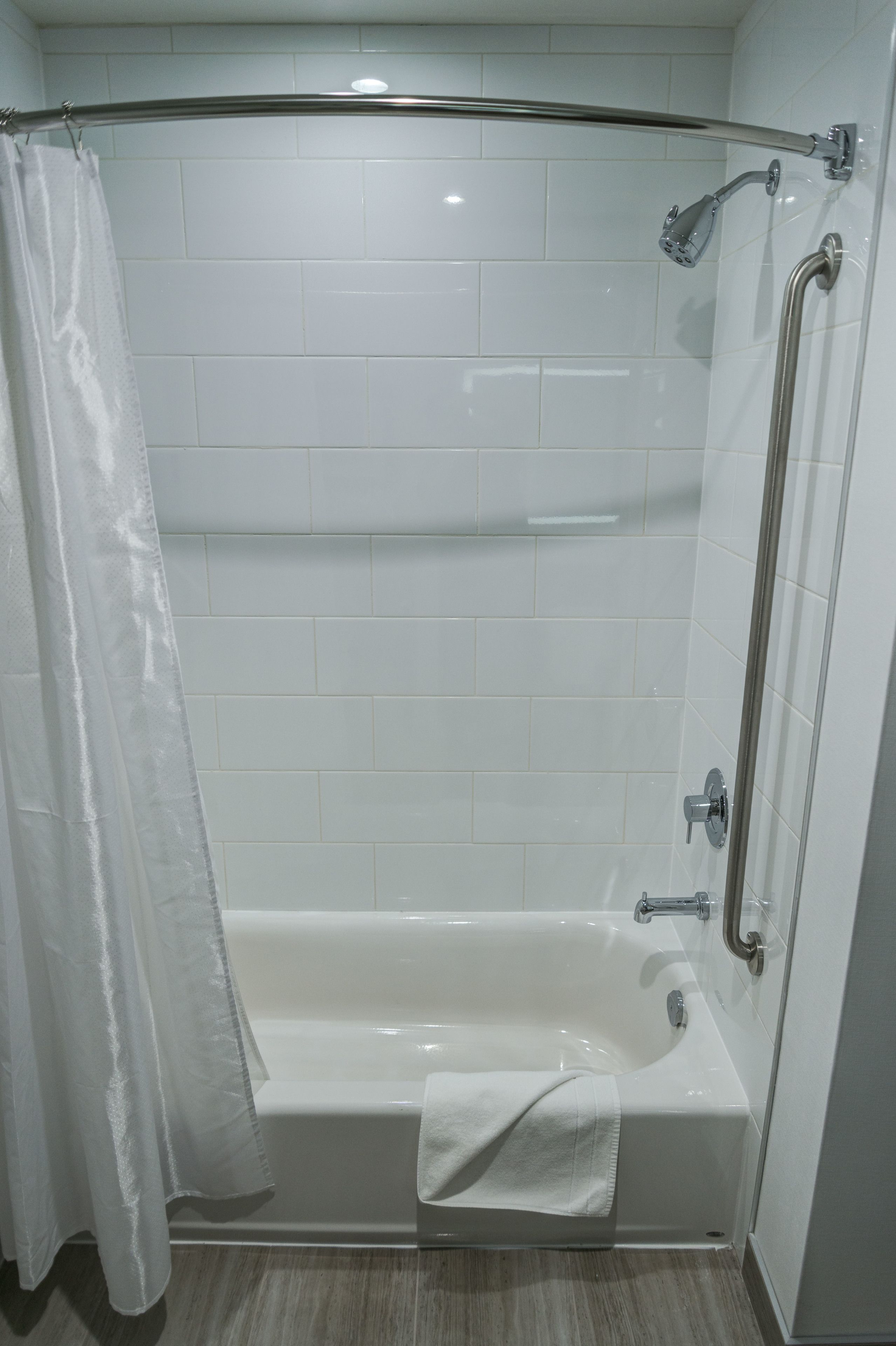 A modern bathroom with a walk-in shower, a glass door, and a white tiled floor.