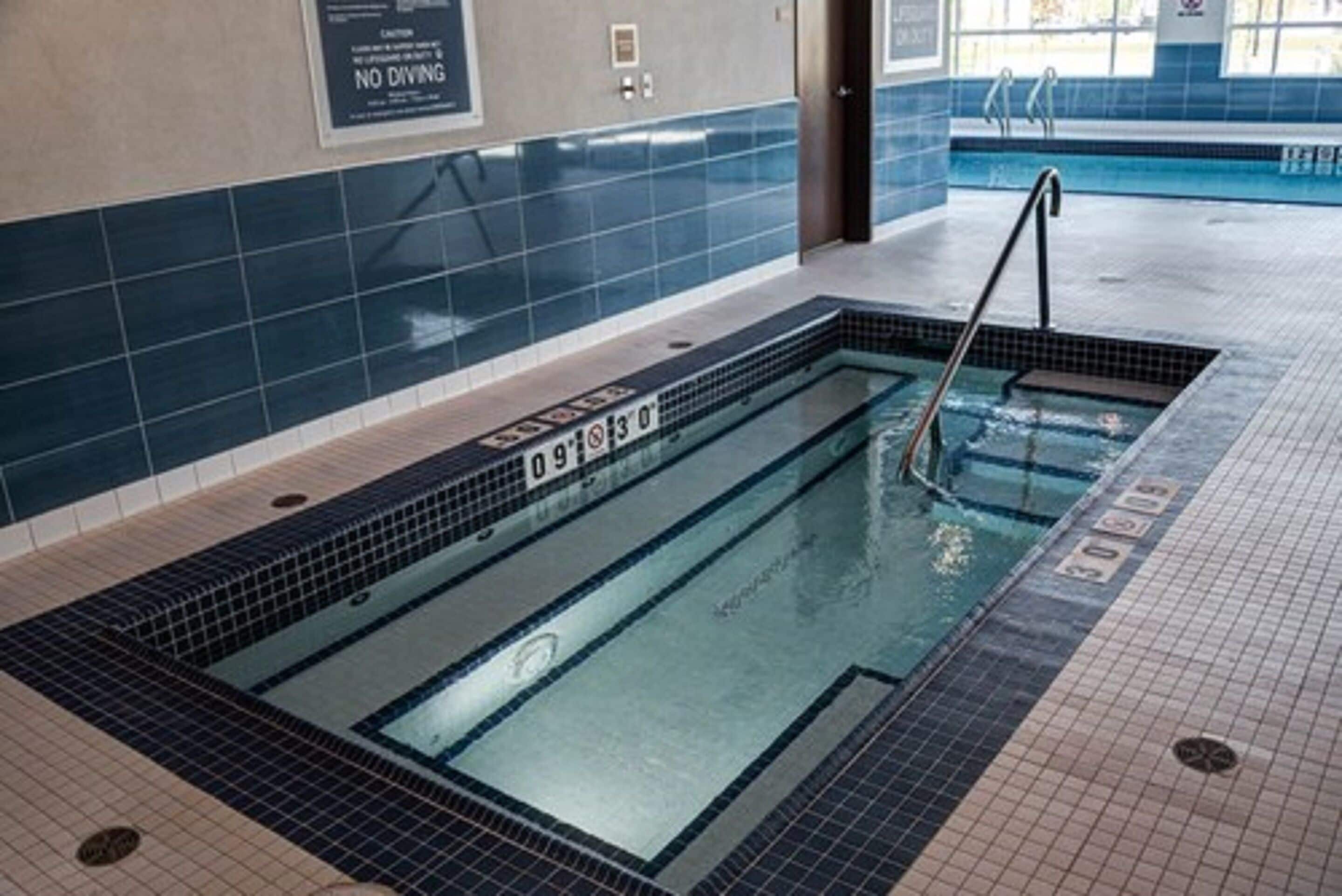 A swimming pool with a no diving sign, tiled walls, and a clear water surface.