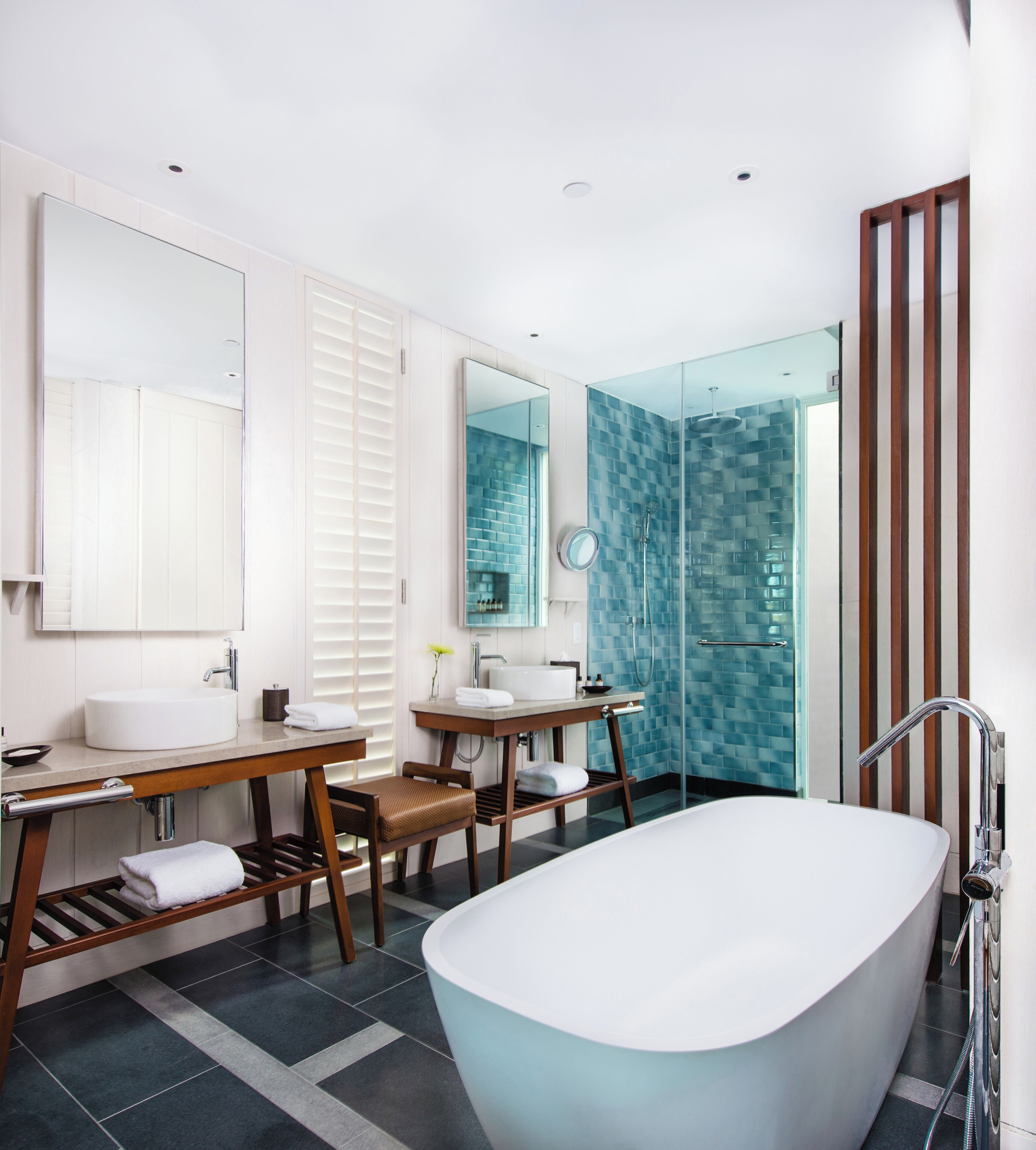 A modern bathroom with a freestanding bathtub, two sinks, a vanity, and a glass-enclosed shower area.