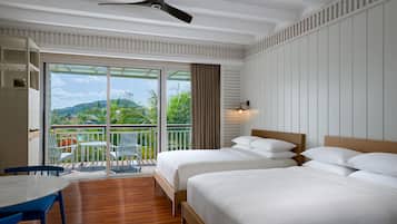 A hotel room with two beds, a balcony with a table and chairs, and a view of greenery.