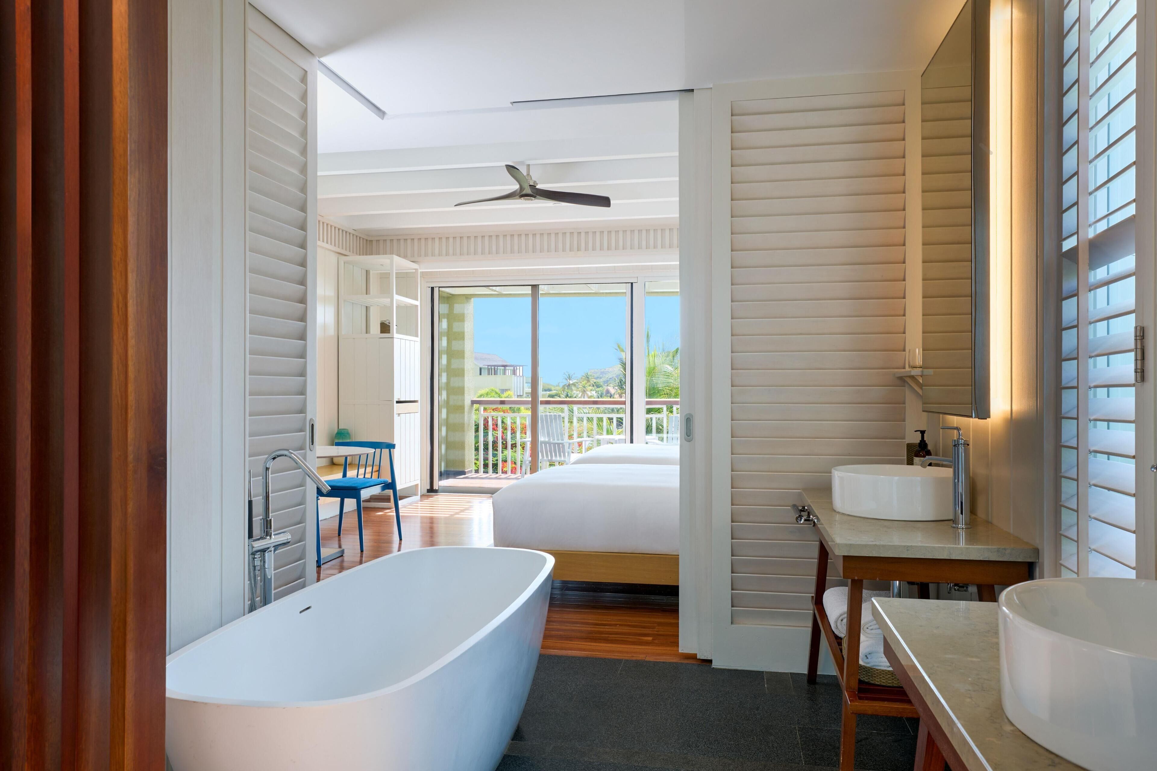A modern bathroom with a freestanding bathtub, a double sink vanity, and a large mirror.