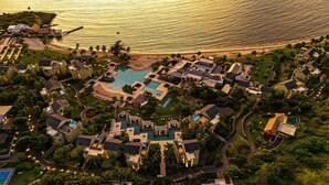 Eine Vogelperspektive eines Resorts mit mehreren Schwimmbecken, direkt am Strand und üppiger Vegetation.