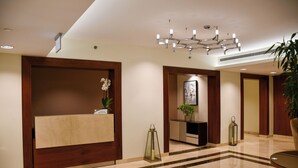A hotel reception area with a marble reception desk, a modern chandelier, and a reception counter. - Intercontinental Doha Residences by IHG (Doha)