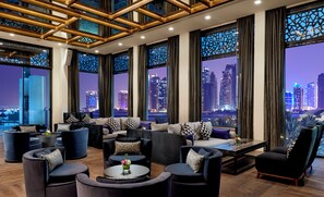 A modern lounge area with multiple seating options, large windows offering city views, and a contemporary ceiling design. - Intercontinental Doha Residences by IHG (Doha)