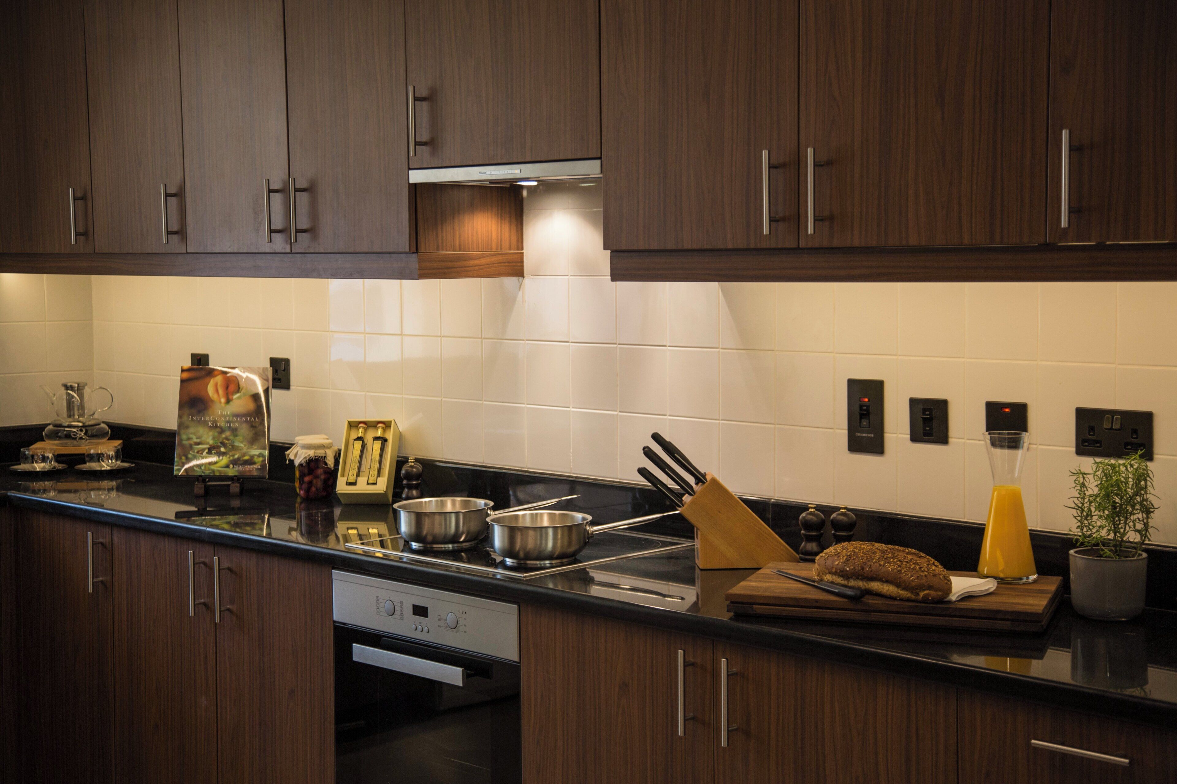 A modern kitchen with dark wood cabinets, a black countertop, and stainless steel appliances.