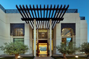 A modern building with a covered entrance, decorative screens, and a well-maintained garden. - Intercontinental Doha Residences by IHG (Doha)