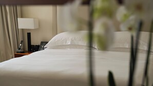 A hotel room with a neatly made bed, a bedside table with a lamp, and a phone. - Intercontinental Doha Residences by IHG (Doha)