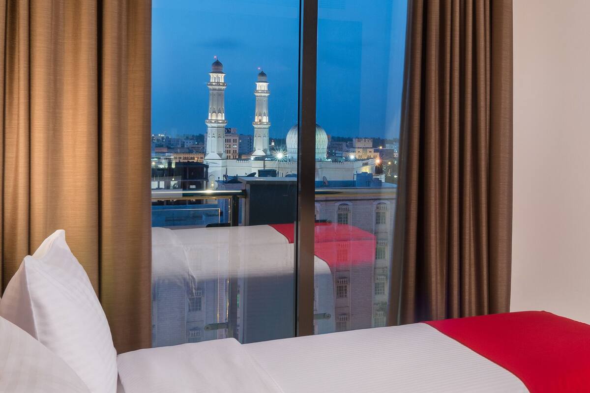 Een hotelkamer met een groot raam, een bed en gordijnen.