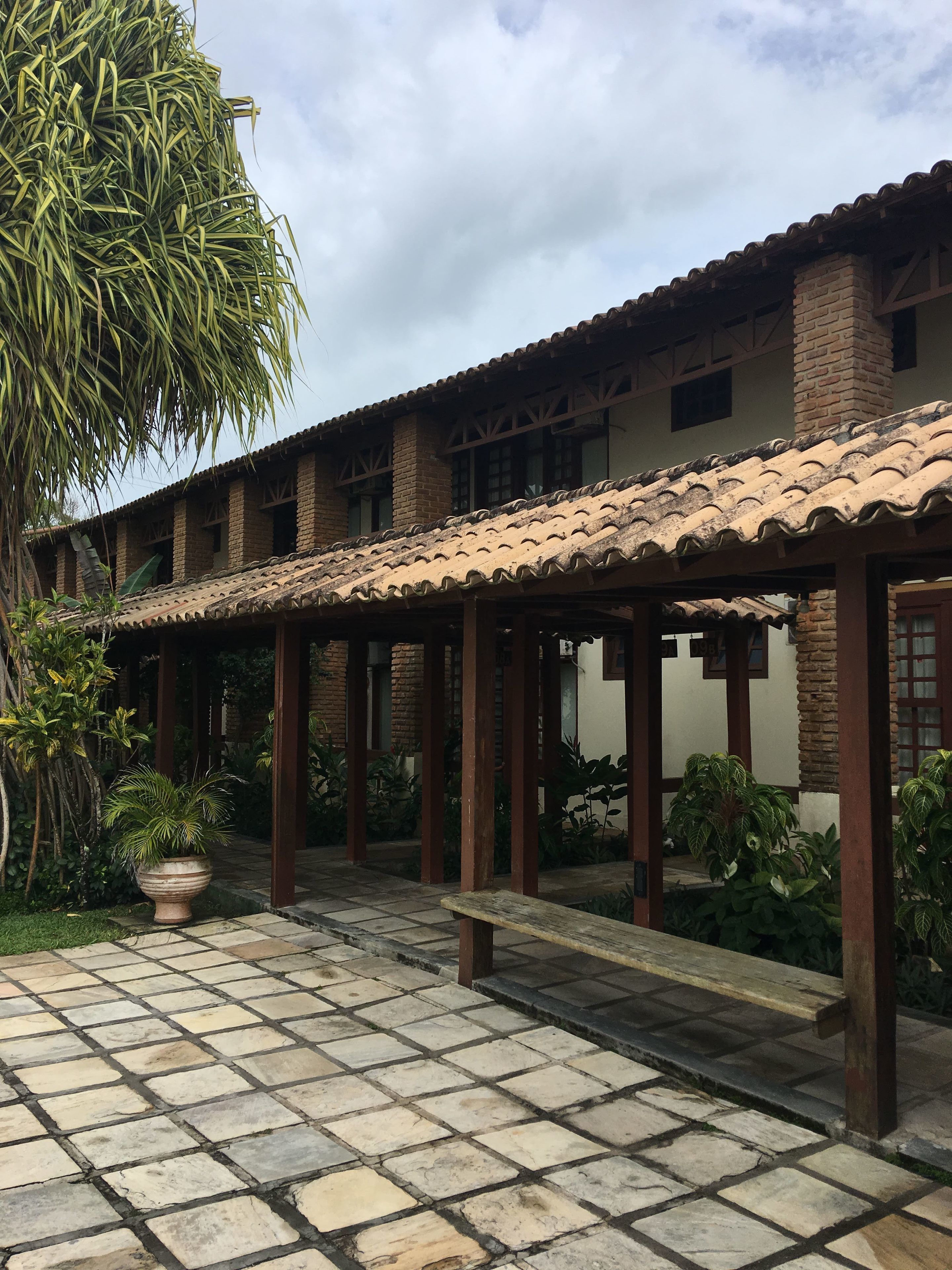 A courtyard with a tiled floor, covered seating area, and potted plants.
