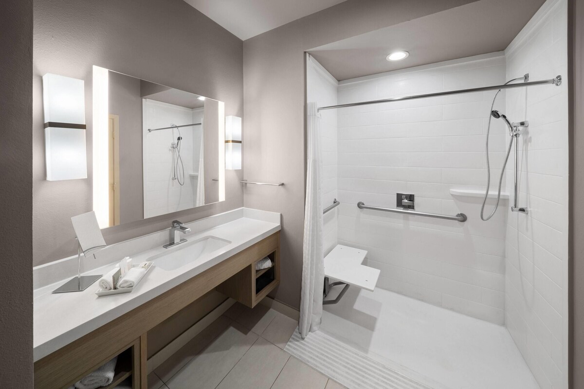 A modern bathroom with a shower, a vanity with a mirror, and a towel rack.