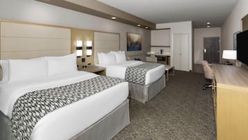 A hotel room with two beds, a desk, a TV, and a bathroom door.