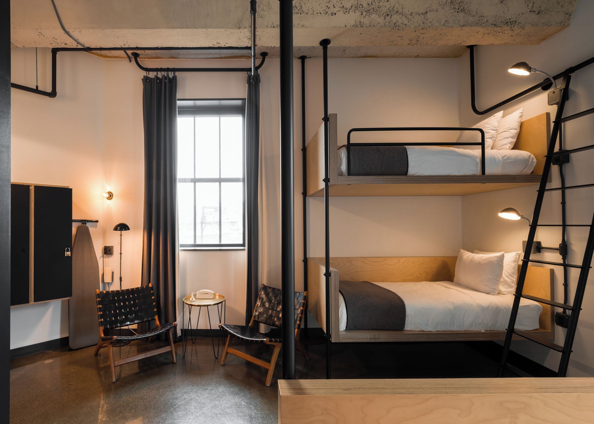 A compact, modern room with bunk beds, a desk, and a chair.