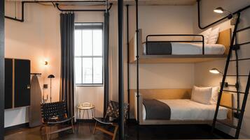 A compact, modern room with bunk beds, a desk, and a chair.