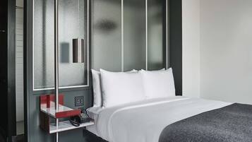 Habitación de hotel con cama, escritorio con teléfono y ventana con vistas.