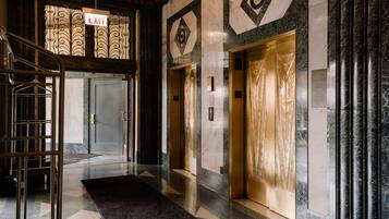 A lobby with a glass door marked "EXIT," two elevators, a reception desk, and a patterned floor.