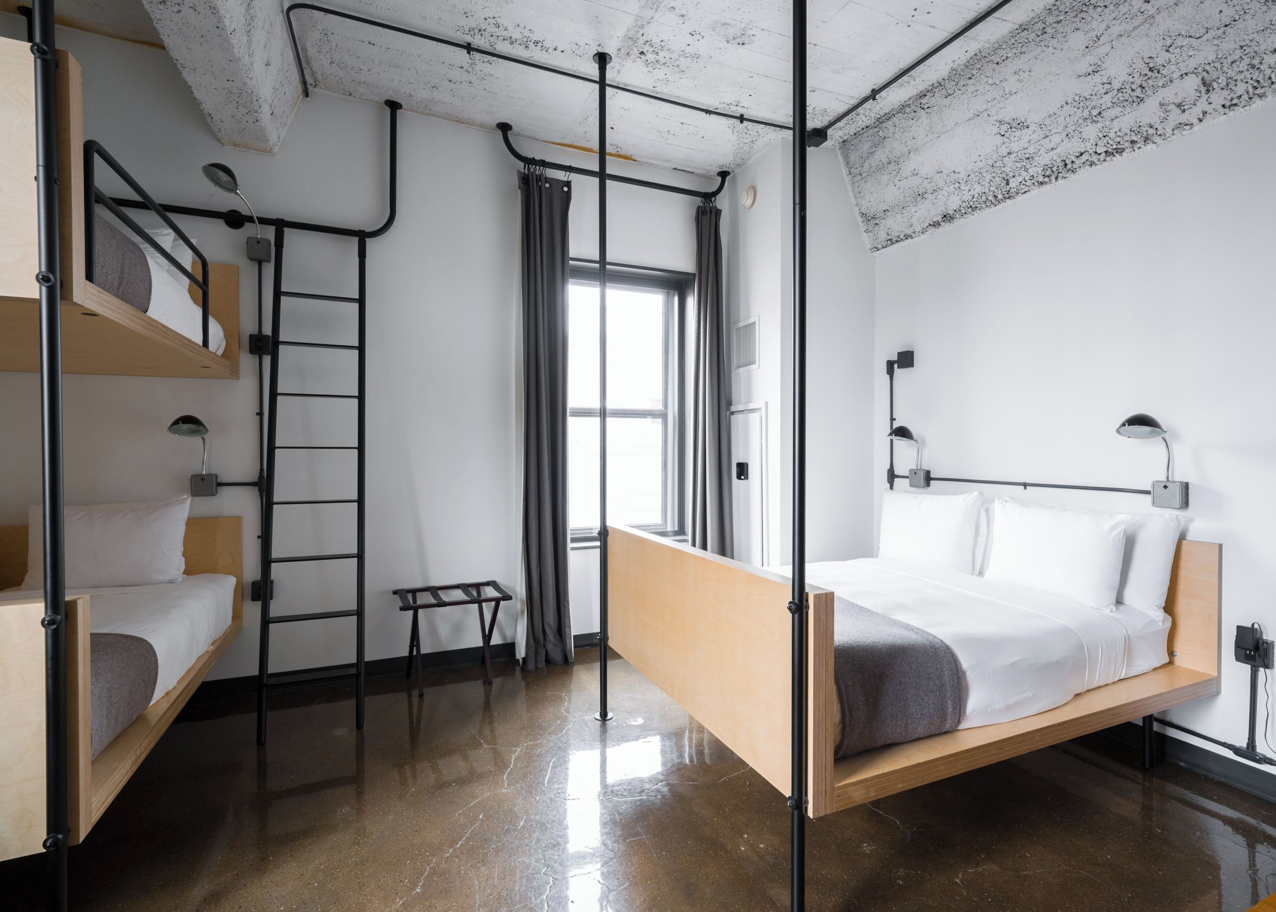 A modern, compact room with a bunk bed, a pull-up bar, a small table, and a window with curtains.