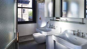 Un baño moderno con dos lavamanos, un inodoro y un ventanal grande.