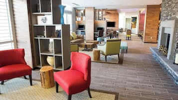 En rymlig entréhall med en öppen spis, bekväma sittplatser och en bokhylla med diverse föremål.
