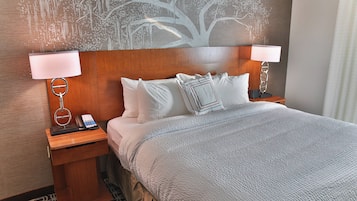 A hotel room with a large bed, two bedside tables with lamps, a phone, and a wall mural.