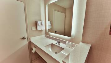 A bathroom with a sink, mirror, and towel rack.