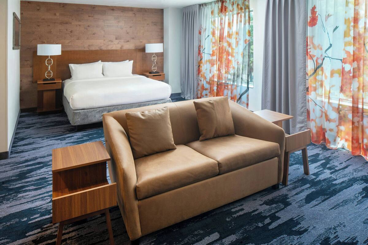 Una habitación de hotel con cama, sofá, una mesita y una mesita de noche.