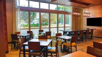 A restaurant with large windows, wooden tables, and chairs.