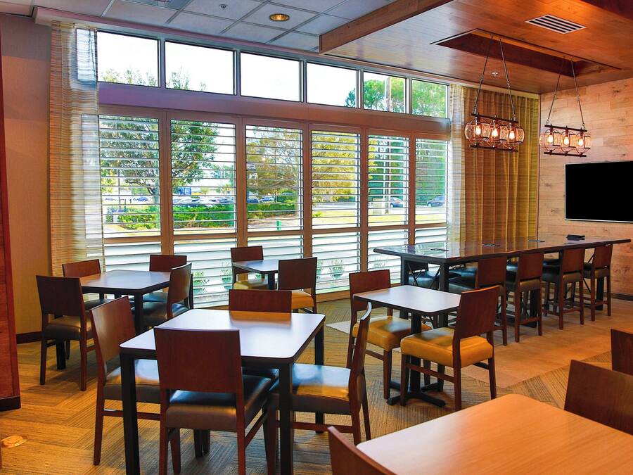 A restaurant with large windows, wooden tables, and chairs.
