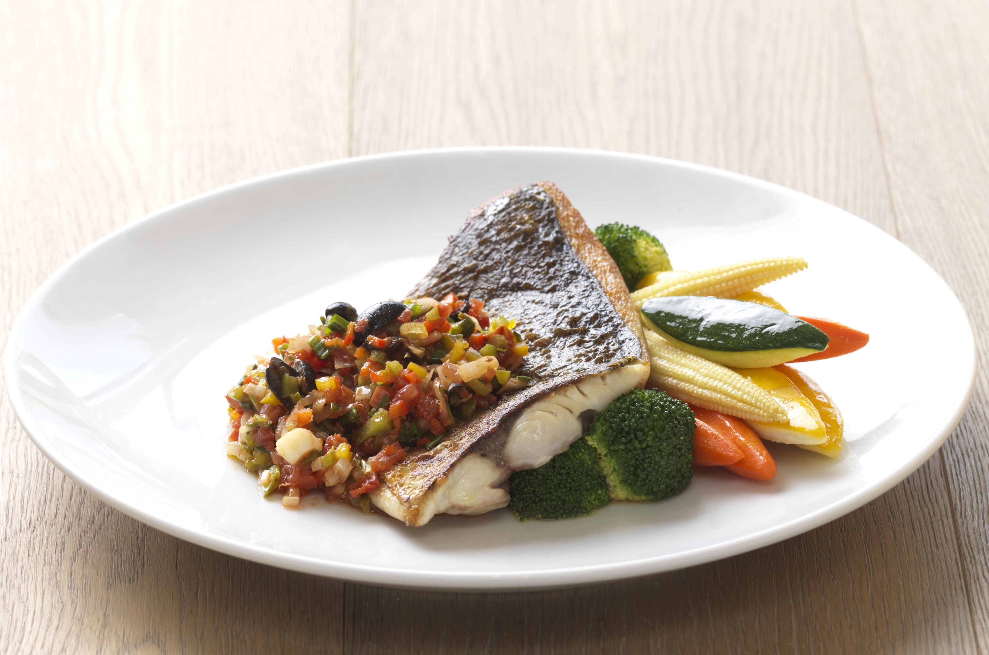 Une assiette blanche contenant un morceau de poisson, des brocolis et un mélange de légumes.