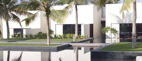 Un edificio moderno con una piscina reflectante y palmeras.