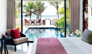 A hotel room with a bed, a small table, a chair, and a view of the ocean. - Al Baleed Resort Salalah by Anantara (Salalah)
