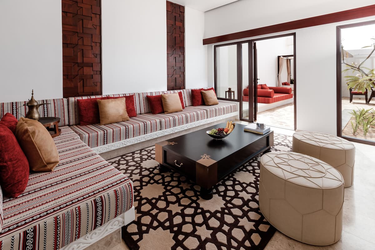 A modern living room with a patterned sofa, a coffee table, and ottomans.
