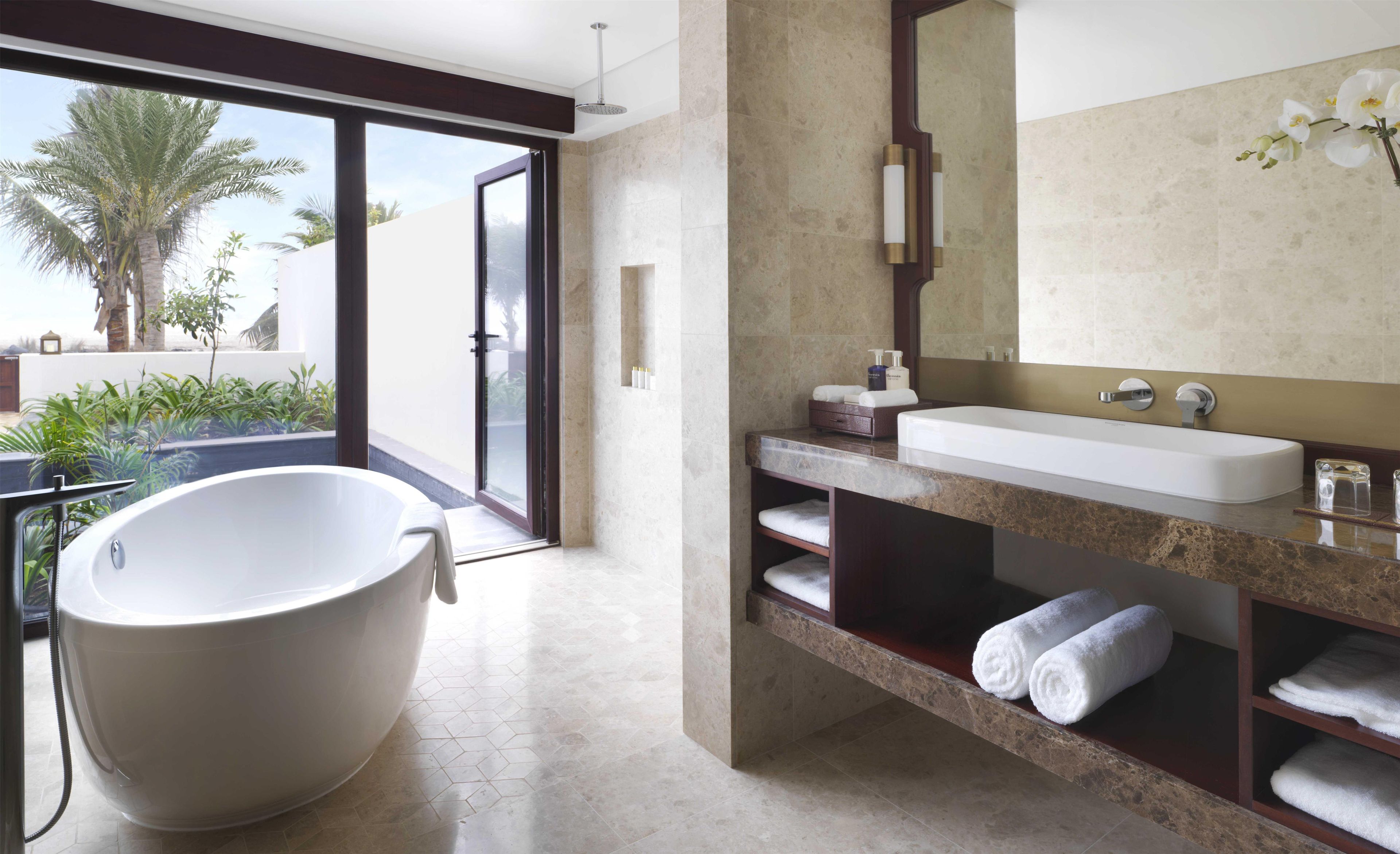 A modern bathroom with a freestanding bathtub, a large mirror, and a sink with a marble countertop.