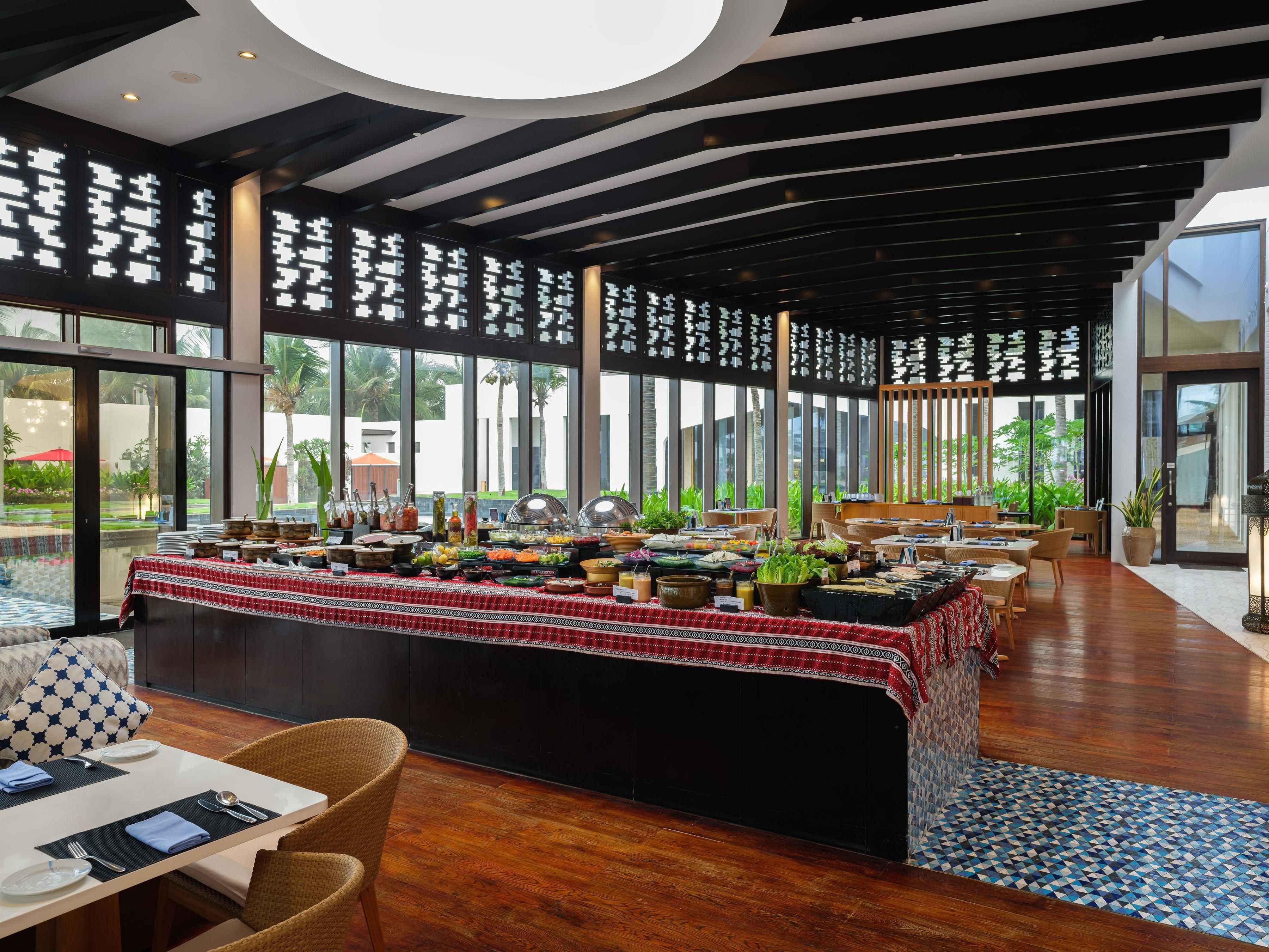 A modern dining area with a buffet setup, large windows, and a wooden floor.