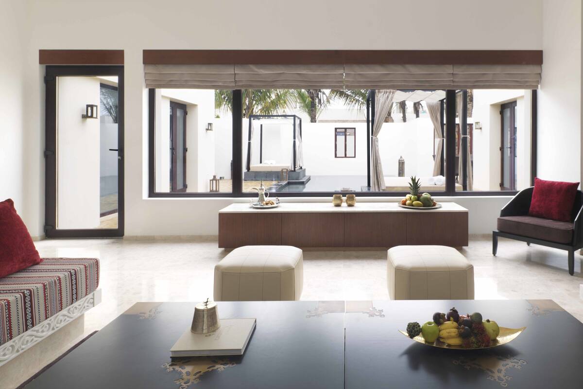 A modern living room with a large window, a sofa, a coffee table, and a fruit bowl.
