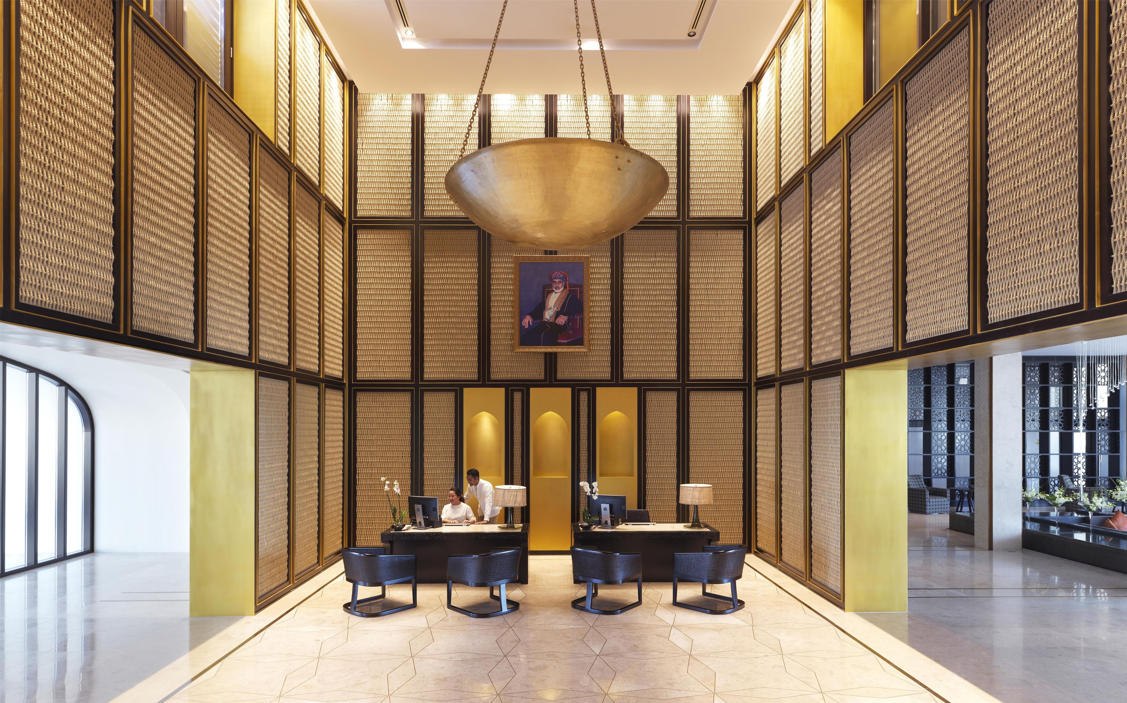 A spacious lobby with a reception desk, seating area, and a large hanging light fixture.