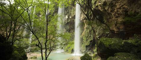 Una cascada natural rodeada de rocas y árboles.